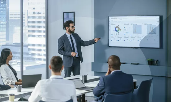 Business meeting with presentation of a Recording Insights dashboard on compliance recording. The dashboard shows aggregated data from customer communication in Microsoft Teams.