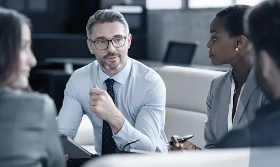 Businessman is in a meeting with three other team colleagues in the financial sector